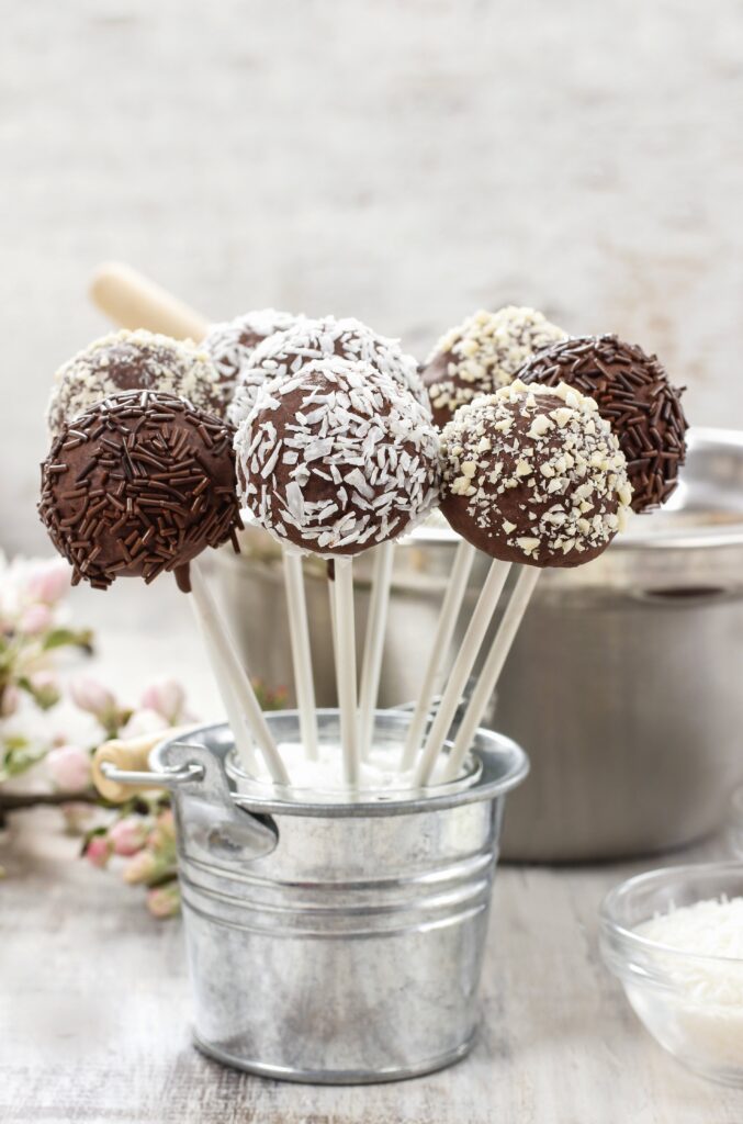 Chocolate cake pops with toppings in a metal bucket.